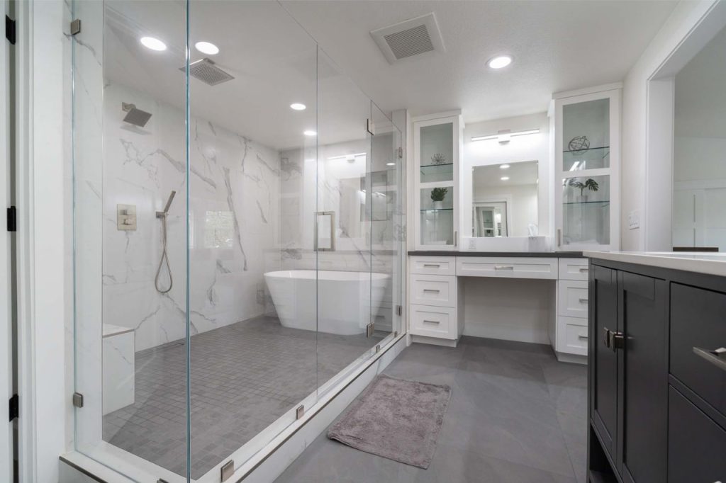 Professional bath remodel contractor Honolulu delivering tub and shower combination with frameless glass enclosure and elegant marble finishes.