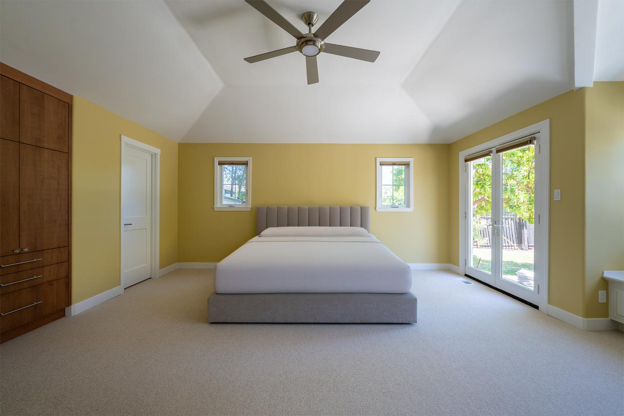 Bright second story addition cost Honolulu bedroom with vaulted ceiling and cheerful yellow accent walls