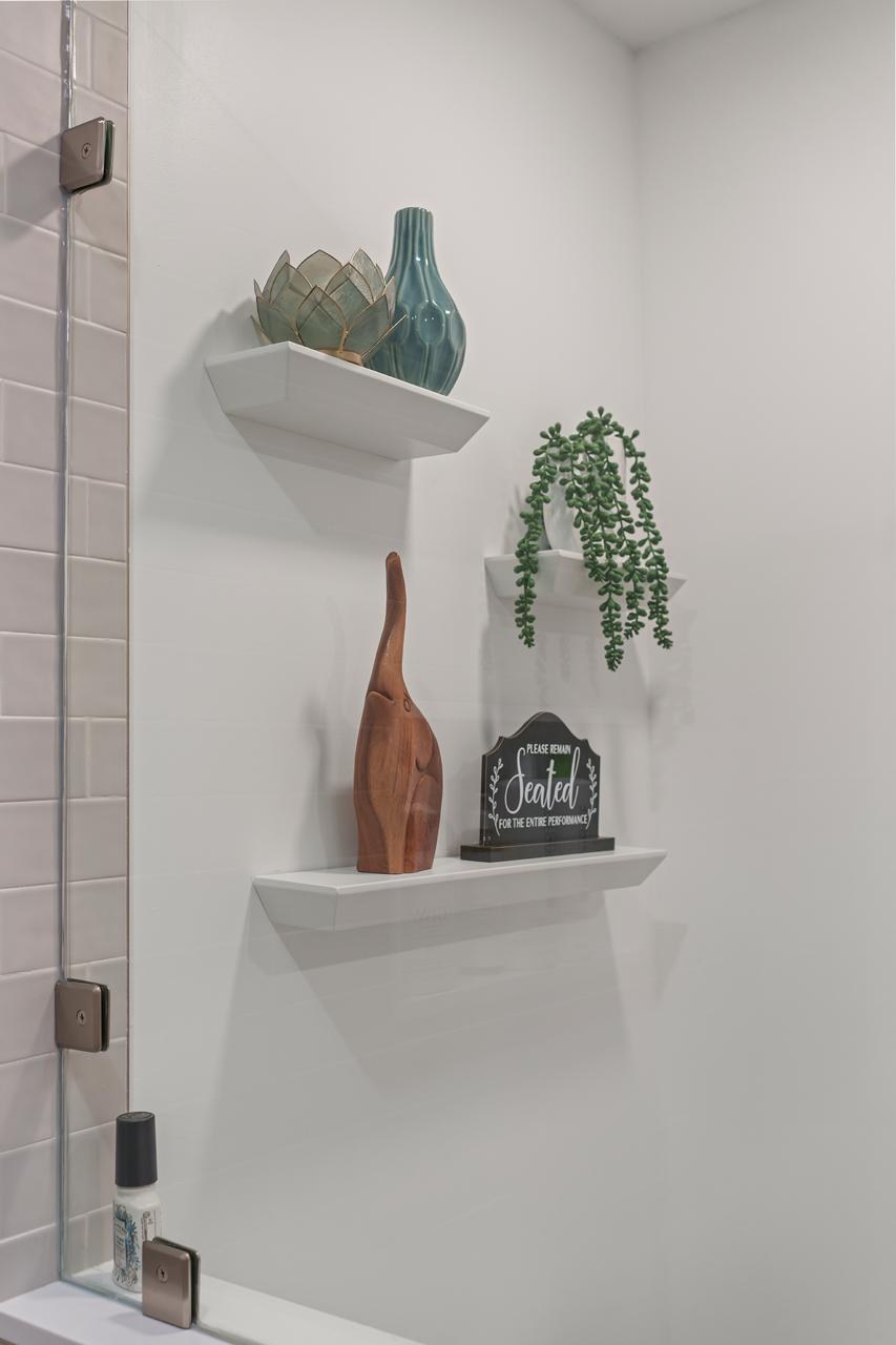 Bathroom after: white floating shelves with decor with painted drywall and white floating shelves, by ASL Remodeling.