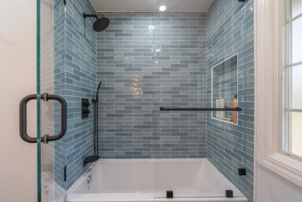 Bathroom: blue glazed subway tile tub shower combo with glazed ceramic subway tile and frameless glass enclosure, by ASL Remodeling.