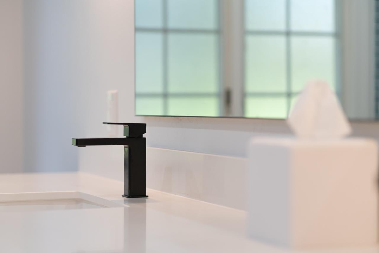Bathroom: matte black square single handle faucet with matte black metal and white quartz countertop, by ASL Remodeling.