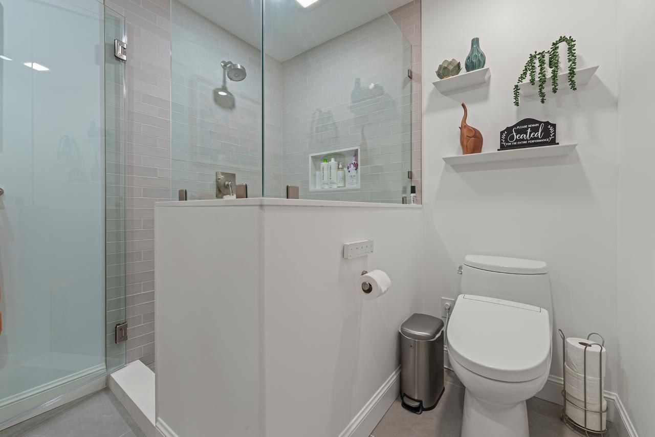 Bathroom after: frameless glass walk in shower enclosure with glass subway tile and large format gray floor tile, by ASL Remodeling.