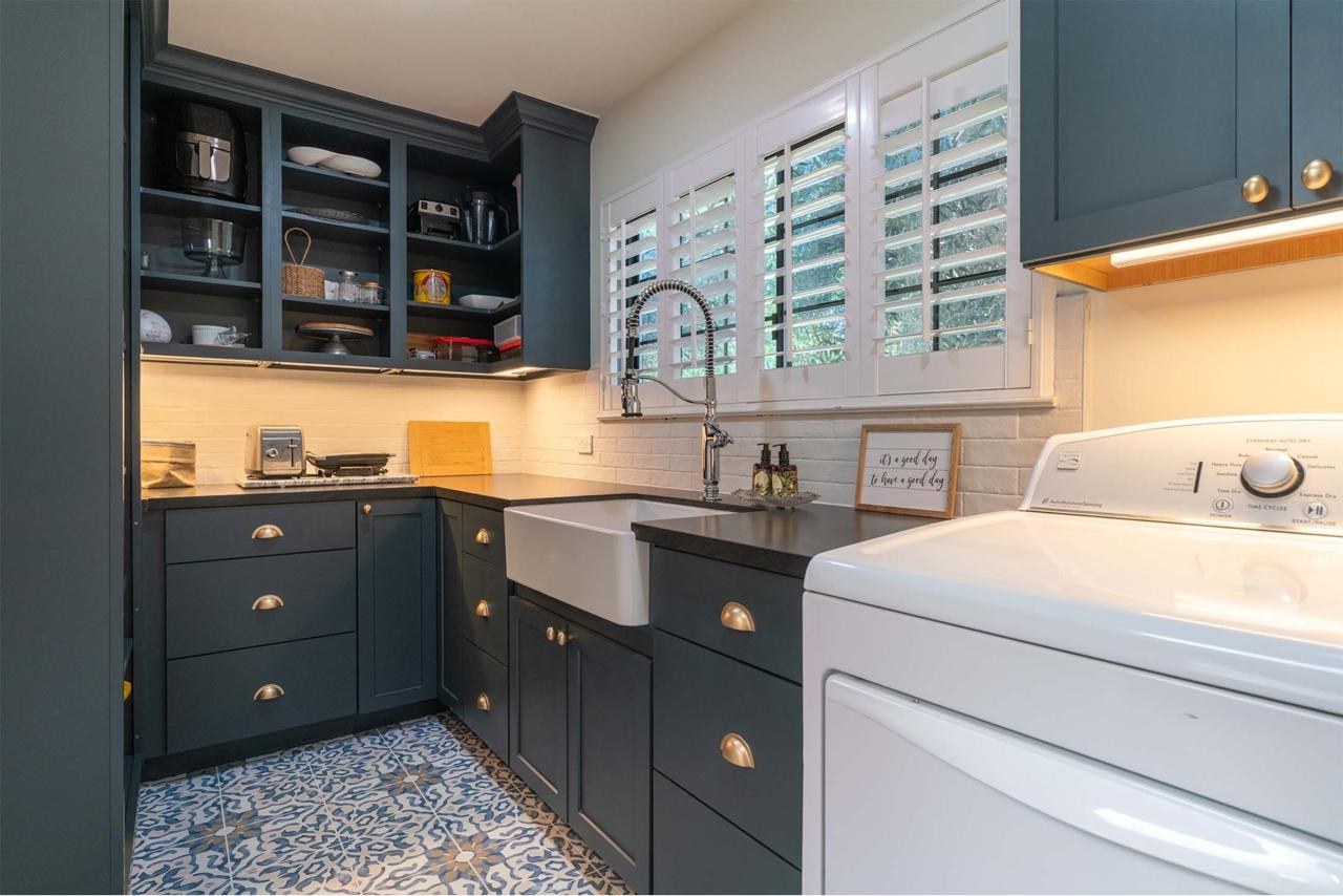 Home remodel laundry room with custom dark cabinetry, patterned tile flooring, open shelving, and layout redesign for improved workflow efficiency