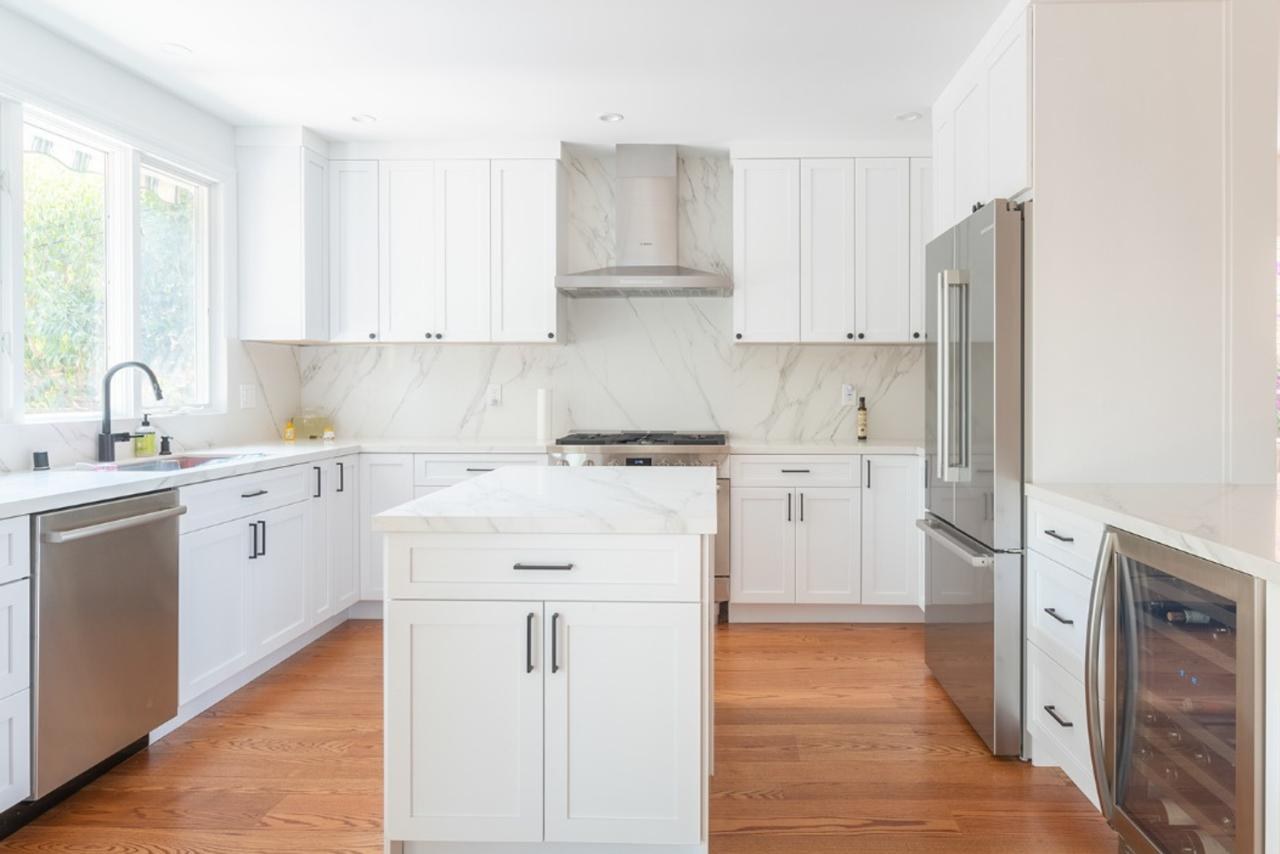 Kitchen: marble slab backsplash with custom range hood with marble slab and white shaker cabinets, by ASL Remodeling.