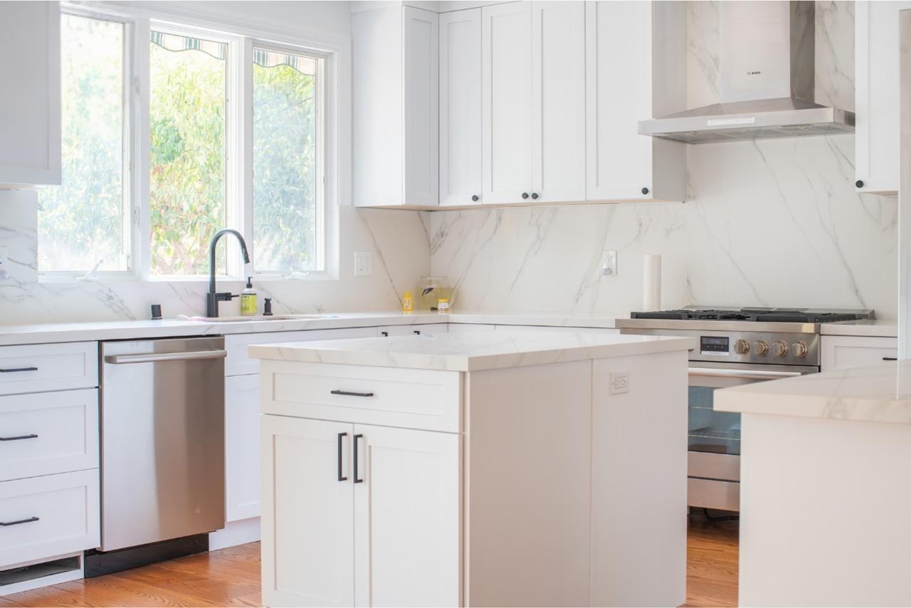 Kitchen: white shaker cabinets with marble backsplash island with quartz countertops and marble slab backsplash, by ASL Remodeling.