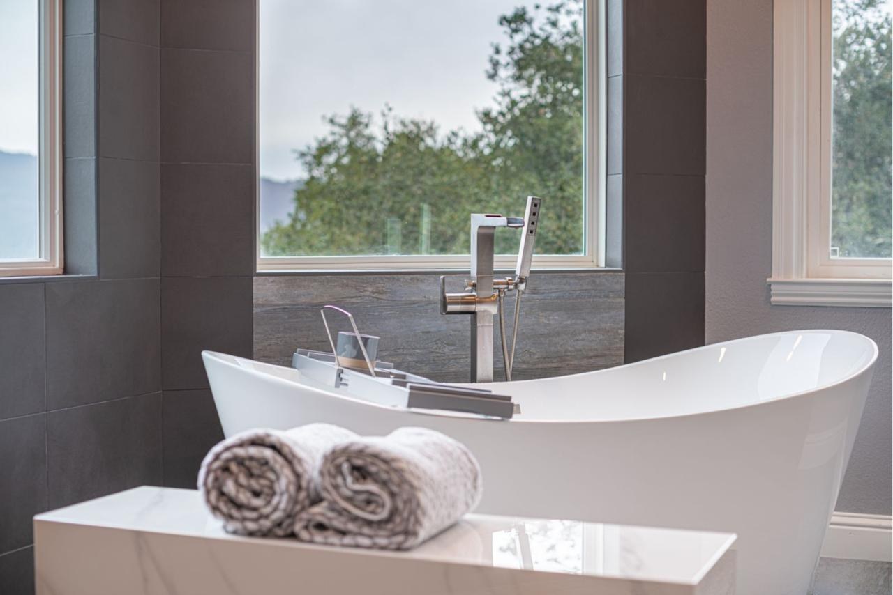 Primary bathroom: freestanding soaking tub with floor mount filler with white acrylic soaking tub and large format dark slate tile, by ASL Remodeling.