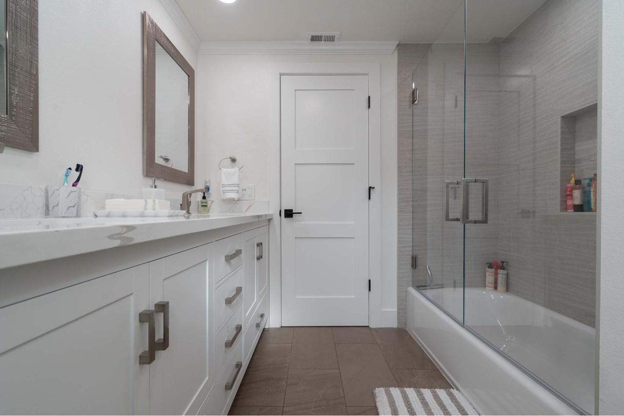 Bathroom with vanity, frameless glass enclosure, recessed niches, and spa-inspired tilework