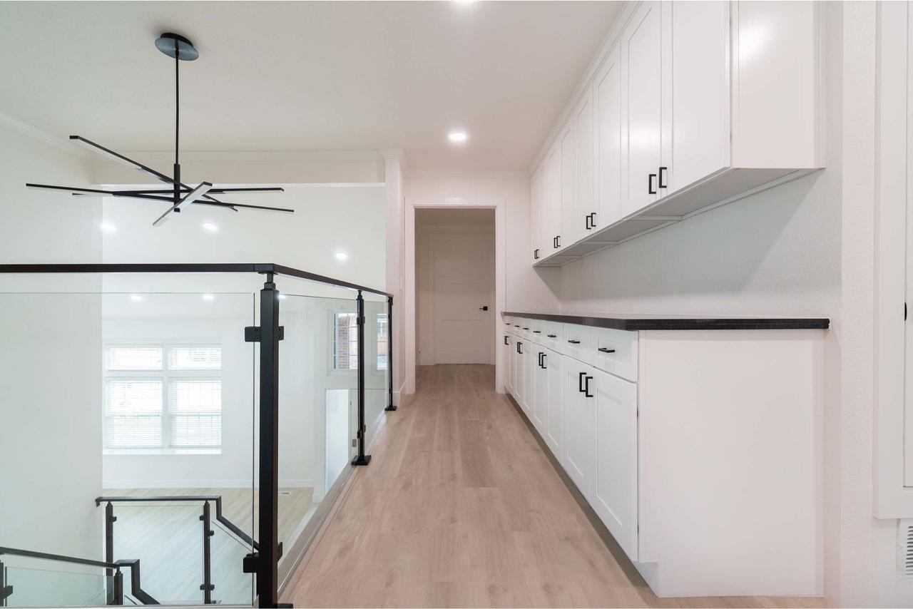 Home remodel with custom cabinetry hallway, white oak hardwood flooring, and matte black glass railing