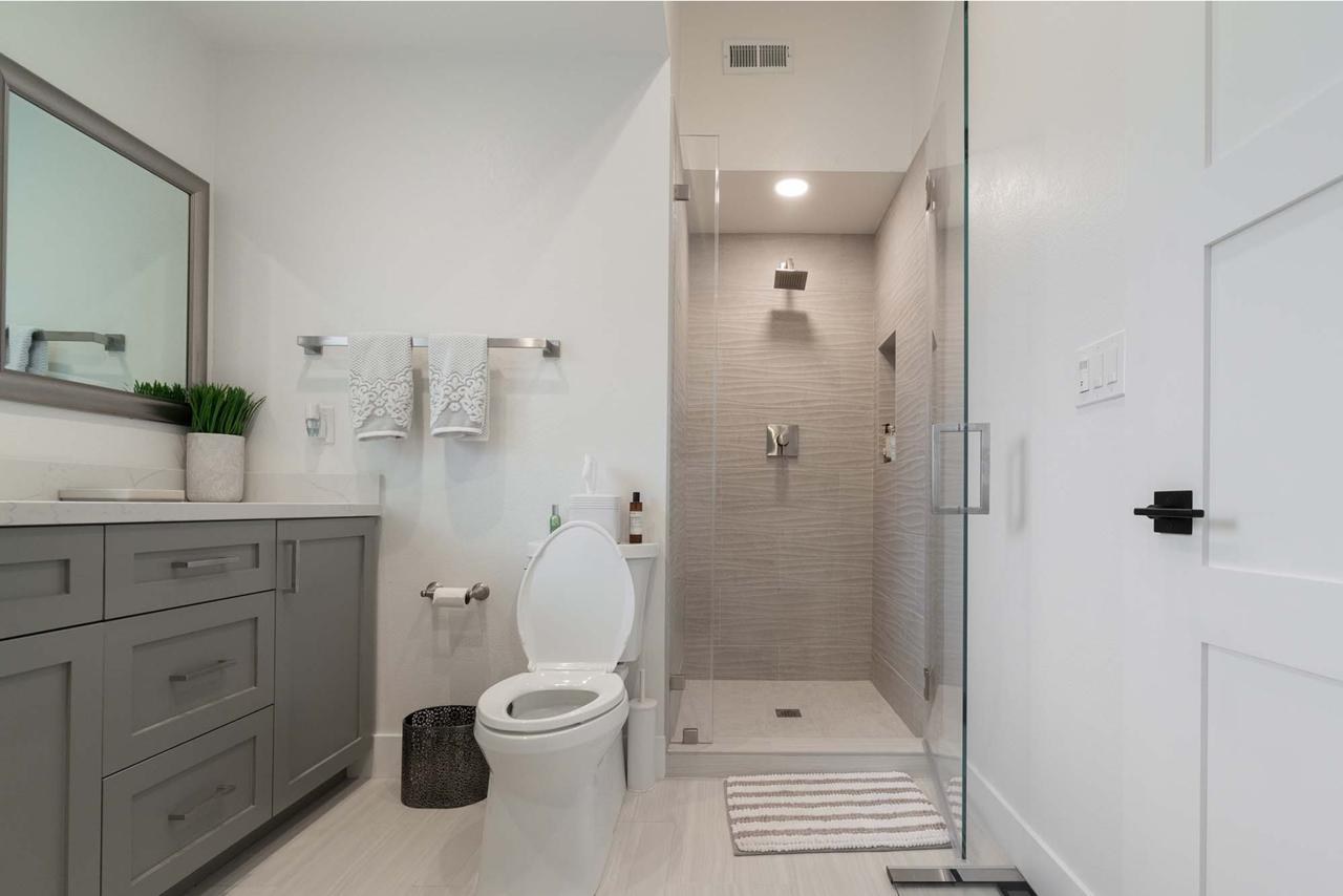 Bathroom remodel with floating vanity, frameless glass shower, textured tilework, and modern fixtures