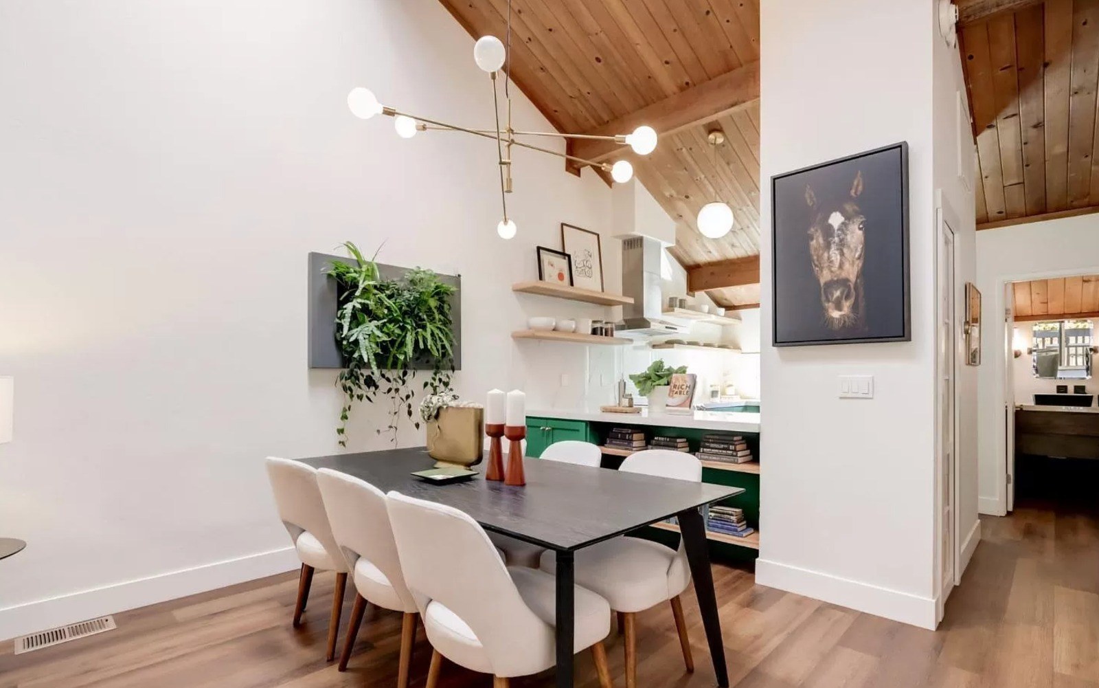 Dining area with wood ceiling, exposed beams, open shelving, and custom green cabinetry in background
