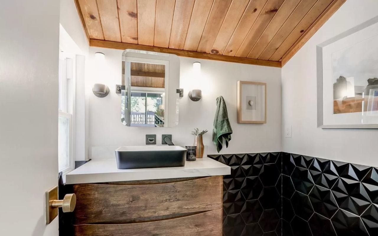 Bathroom featuring wood ceiling, dramatic 3D tile wall treatment, vessel sink, and matte black fixtures