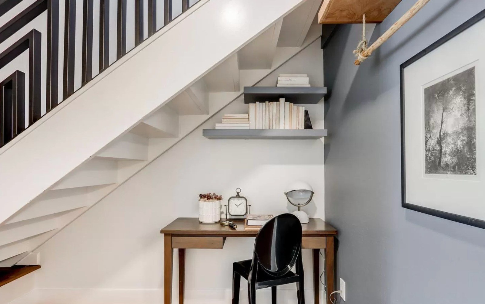 Home with under-stair workspace, floating shelves, modern stair railing, and efficient use of space