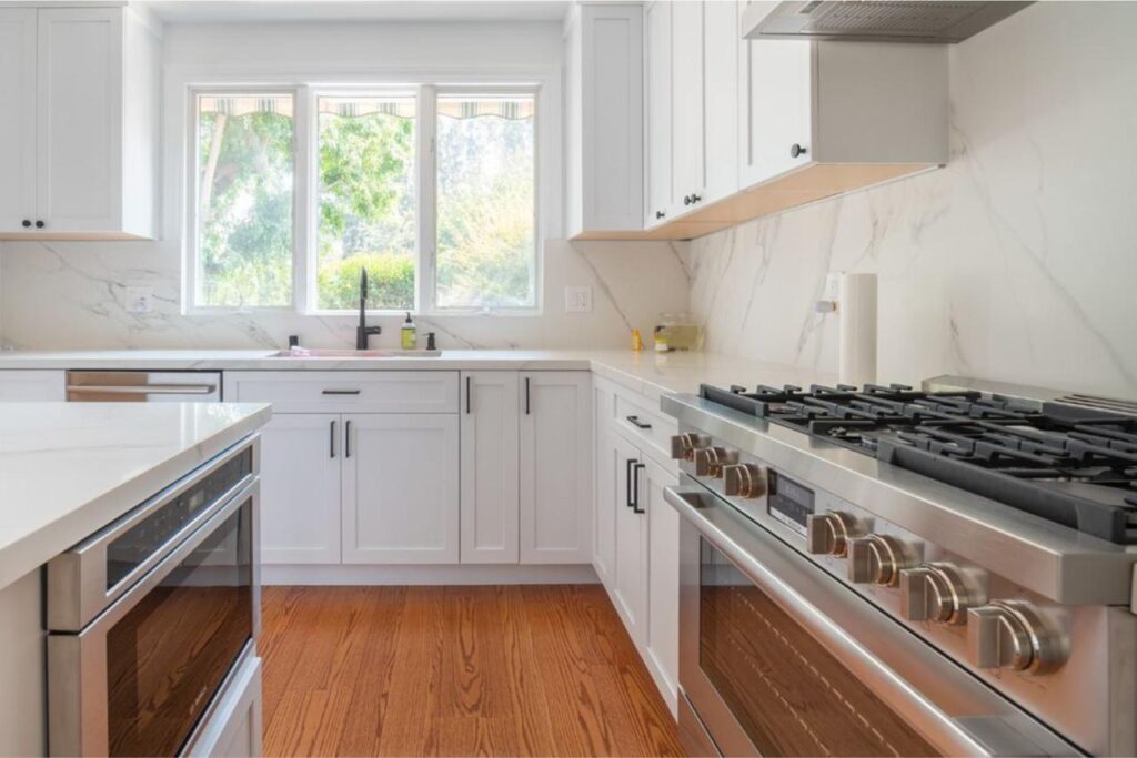 Kitchen: professional gas range with marble backsplash with white quartz countertops and marble slab backsplash, by ASL Remodeling.