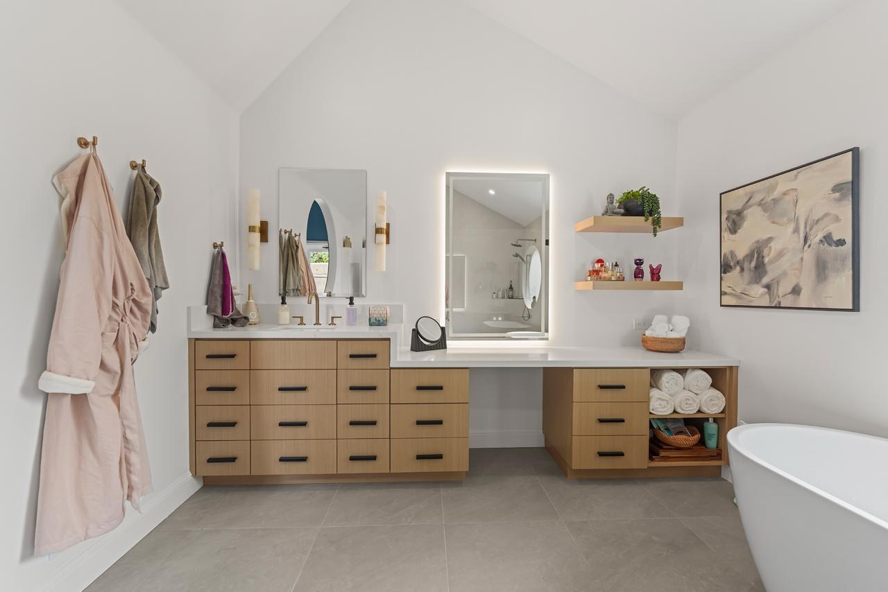 Primary bathroom after: floating wood vanity with makeup counter with white oak cabinetry and quartz countertop, by ASL Remodeling.