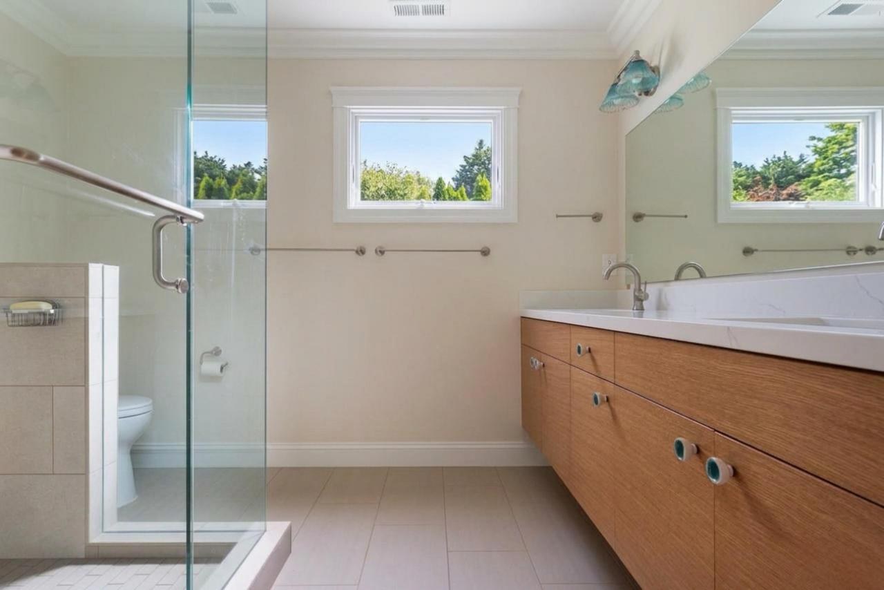 Primary bathroom after: floating wood vanity with quartz countertop with white oak veneer cabinetry and quartz countertop, by ASL Remodeling.