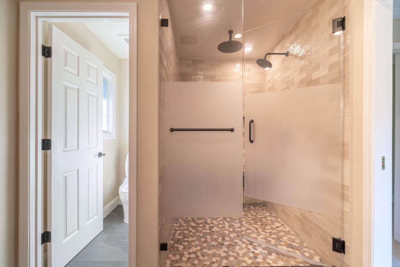 Primary bathroom: frameless glass walk in shower with dual heads with frameless glass and mosaic pebble floor tile, by ASL Remodeling.