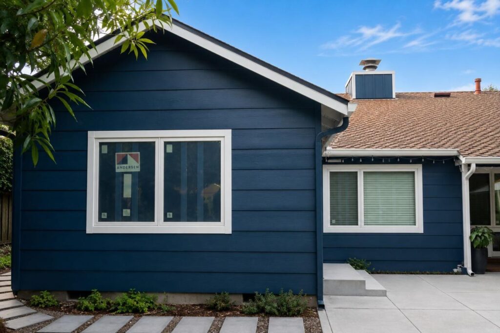 Exterior after: bold navy blue lap siding with white trim windows with painted lap siding and asphalt shingle roofing, by ASL Remodeling.