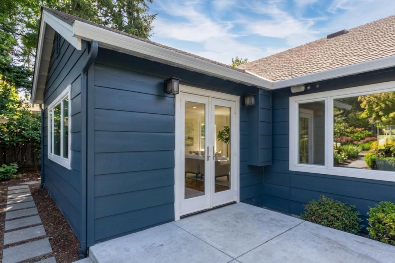 Exterior after: white french doors on navy siding addition with painted wood lap siding and composite asphalt shingles, by ASL Remodeling.
