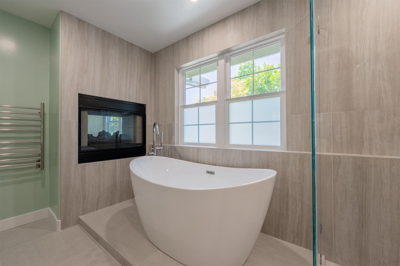 Freestanding soaking tub with a chrome floor-mounted filler in a spa-style master bathroom