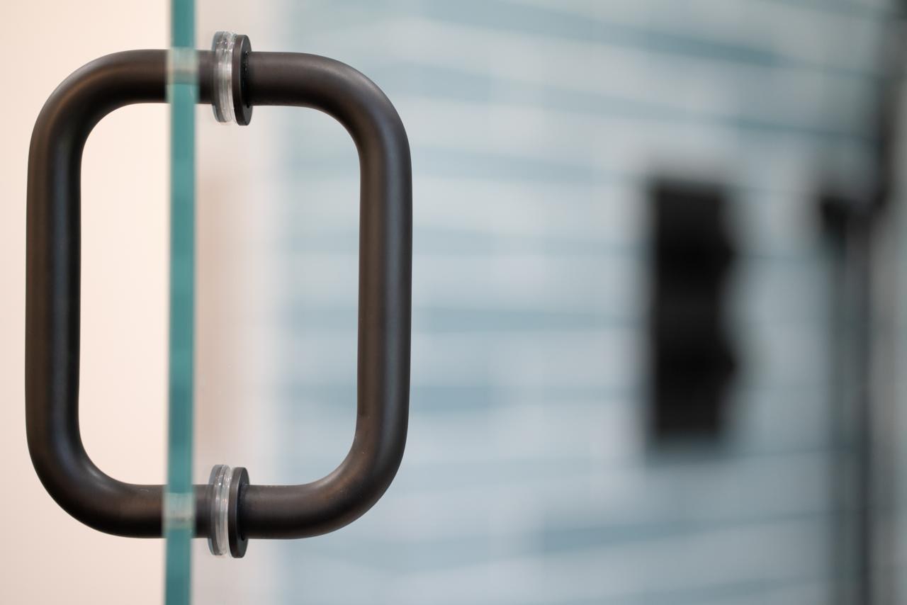 Bathroom: matte black frameless shower door pull with matte black metal and tempered glass, by ASL Remodeling.