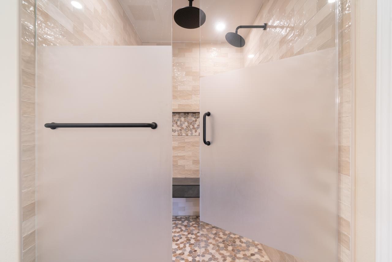 Bathroom: dual rain head walk in shower enclosure with frosted glass panels and pebble stone floor tile, by ASL Remodeling.
