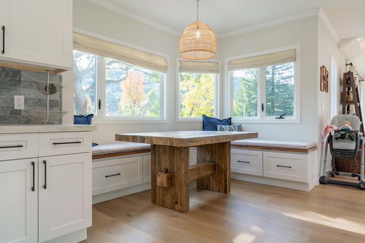 Home remodel featuring completed kitchen with custom white cabinetry, wood island, and breakfast nook with natural lighting by ASL Remodeling