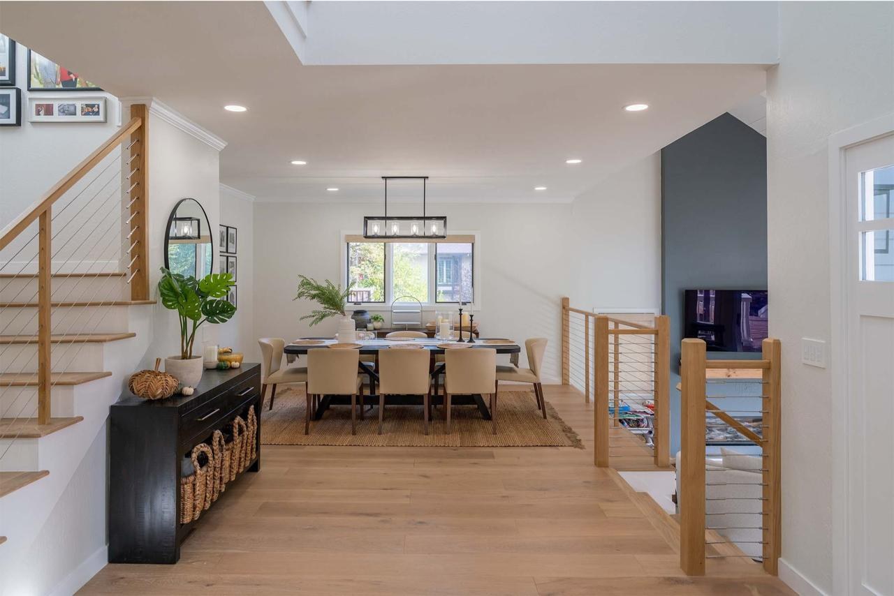 Dining room with vaulted ceiling, shiplap walls, modern staircase with cable railing, and engineered white oak flooring