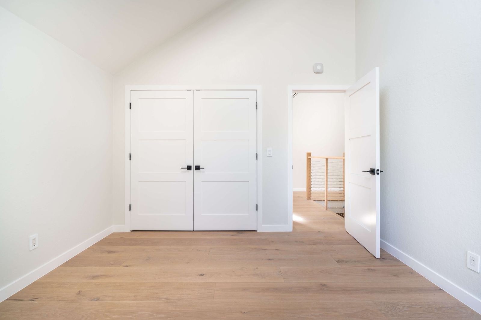 Bedroom featuring vaulted ceiling, double closet doors, engineered white oak hardwood flooring, and modern finishes