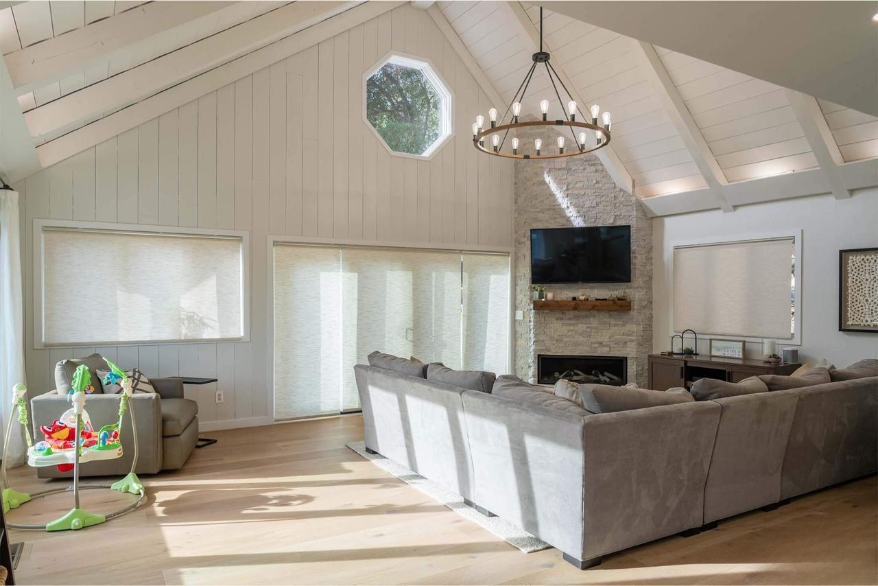 Living room with vaulted shiplap ceiling, stone fireplace surround, modern lighting, and engineered white oak flooring